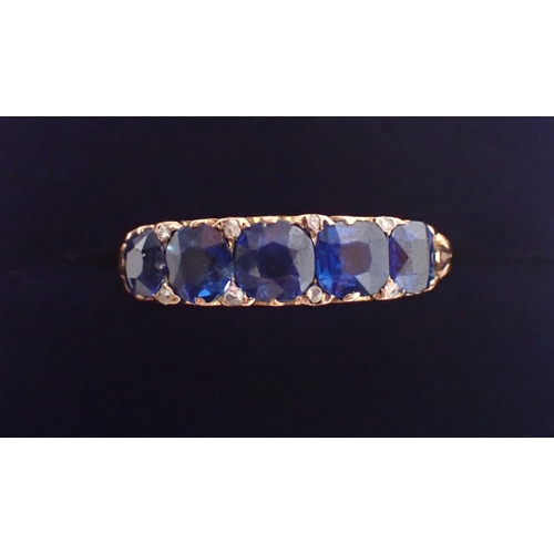 389 - An unmarked gold ring set five sapphires with diamond accents, size Q/R, 3.2g, tested as 9 carat