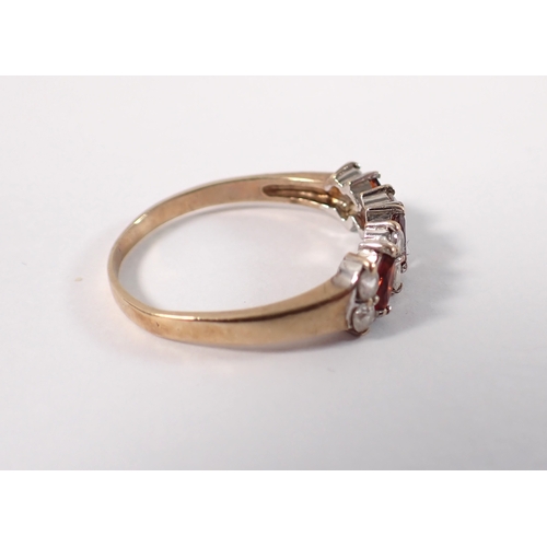 402 - A 9ct gold ring set three garnets interspersed pairs of white stones, size N, 2.2g