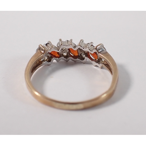402 - A 9ct gold ring set three garnets interspersed pairs of white stones, size N, 2.2g