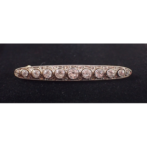 406 - An 18ct yellow and white metal bar brooch set graduated row of nine diamonds, central diamond 3.6mm,... 