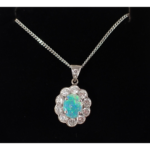 414 - An 18ct white gold oval cut opal pendant with diamond surround on 9ct gold chain, opal 9 x 7mm, diam... 