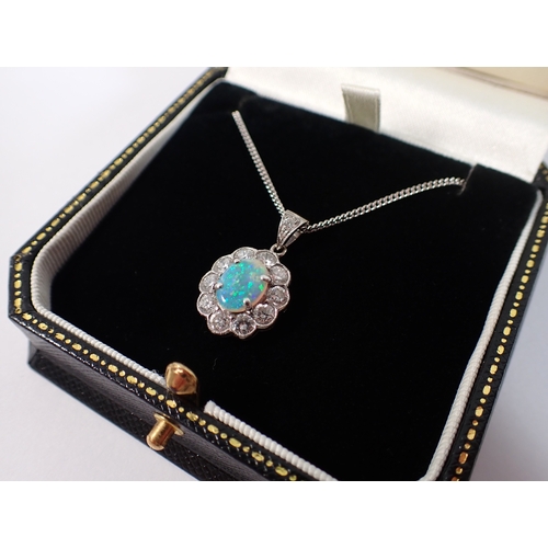 414 - An 18ct white gold oval cut opal pendant with diamond surround on 9ct gold chain, opal 9 x 7mm, diam... 