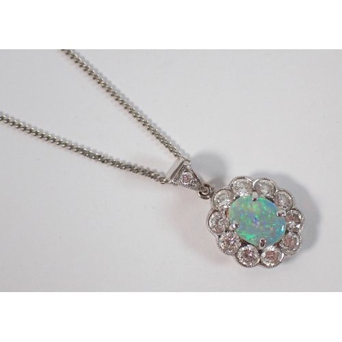 414 - An 18ct white gold oval cut opal pendant with diamond surround on 9ct gold chain, opal 9 x 7mm, diam... 