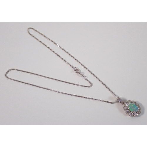 414 - An 18ct white gold oval cut opal pendant with diamond surround on 9ct gold chain, opal 9 x 7mm, diam... 
