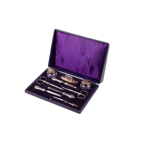 38 - A silver and steel manicure set. Nine pieces, including silver lidded bottles, buff, scissors, etc, ... 