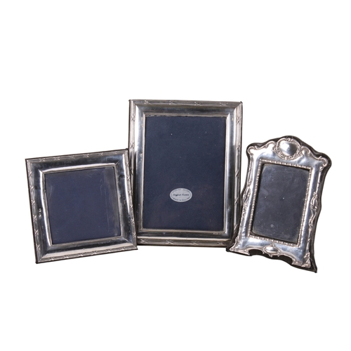49 - Three silver photograph frames. Two of matching pattern with crosses reeded outer border, the third ... 