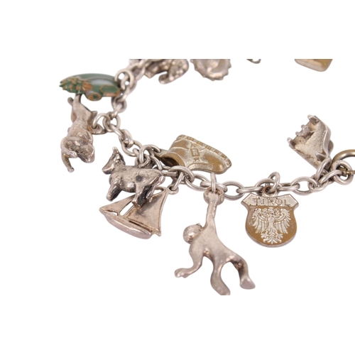 245 - A white metal charm bracelet. Charms including animals, a yacht, cow bell, etc, gross weight 33g.