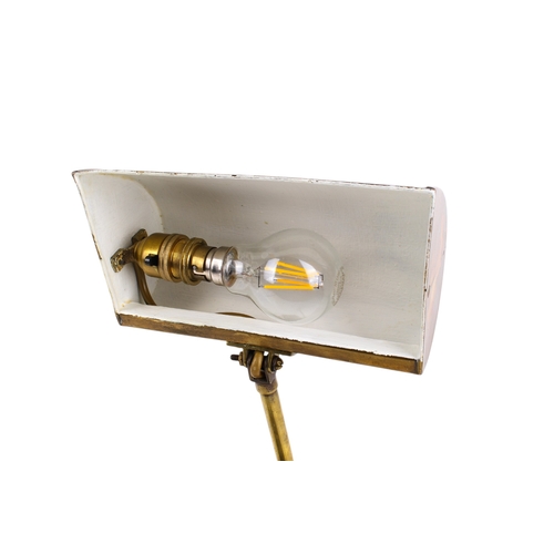 221 - A vintage brass desk lamp. Having a domed shade, the interior painted white, the adjustable stand mo... 