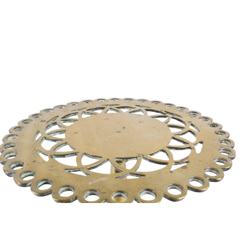 257 - A Victorian brass trivet. The circular top with pierced decoration and a shaped edge, mounted on a s... 