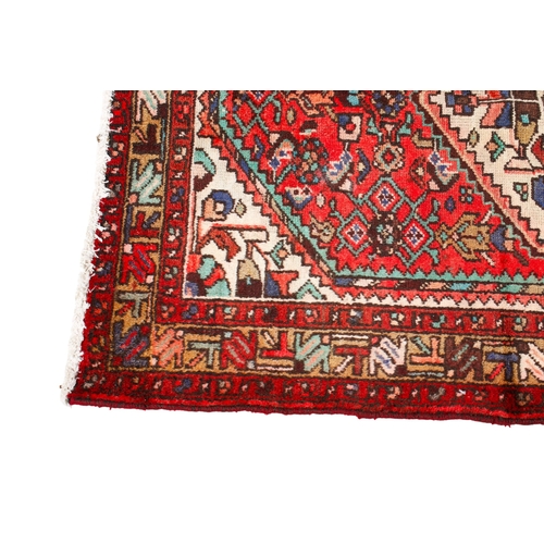 454 - A vintage Persian rug. The central cream diamond motif with floral details, mounted on a red ground,... 