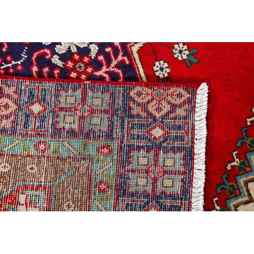 456 - A vintage Persian rug. The central panel featuring a blue medallion surrounded by flowers and on a r... 