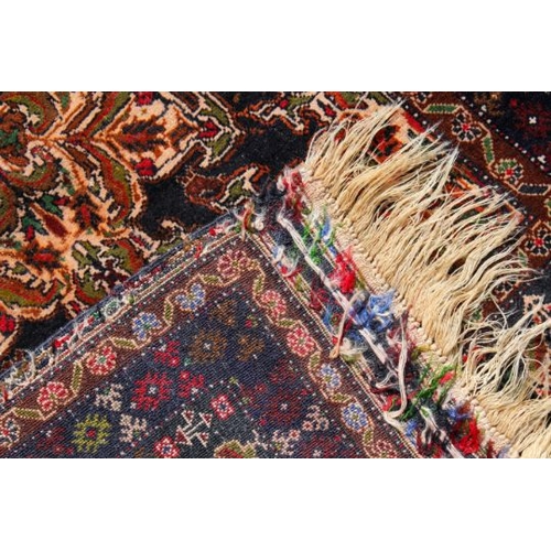 453 - A rust red and green patterned prayer rug. The shaped central motif on a dark blue ground with multi... 