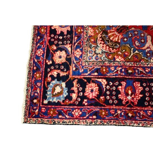 470 - A Persian style wool rug on a red ground. With multiple geometric border on a blue ground. 260cm x 1... 