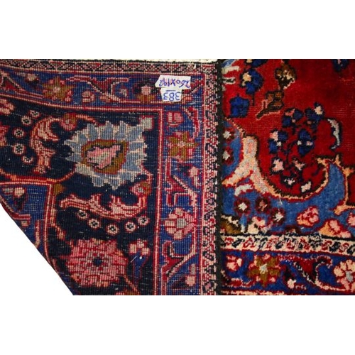 470 - A Persian style wool rug on a red ground. With multiple geometric border on a blue ground. 260cm x 1... 