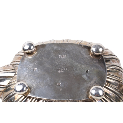 6 - An early 20th century silver teapot. With scrolling border interspersed with flowers, over a ribbed ... 