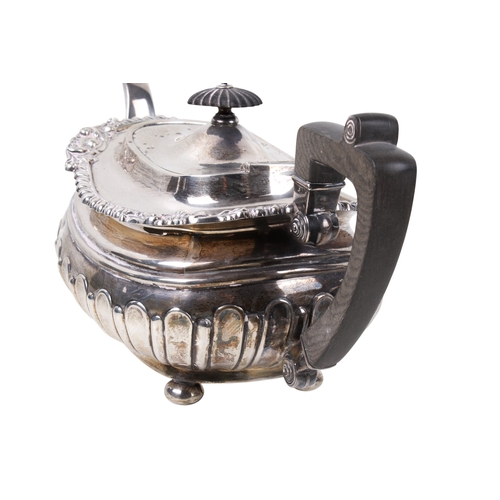 6 - An early 20th century silver teapot. With scrolling border interspersed with flowers, over a ribbed ... 
