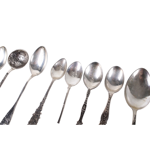 69 - A collection of white metal teaspoons. The handles decorated with embossed flowers, architecture and... 