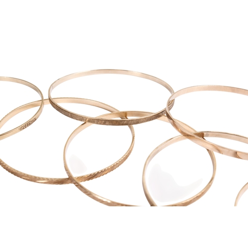 198 - Seven 9ct gold (tested) narrow flat bangles of various designs, some marked. Gross weight 49.8g.