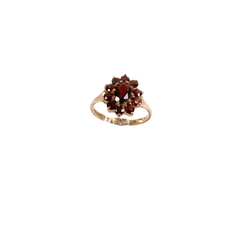 129 - A 9ct gold garnet cluster ring. Set with ten small stones around the central oval faceted stone, siz... 