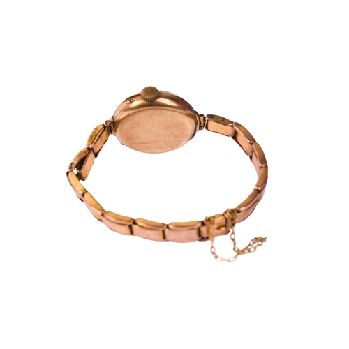 395 - A 9ct gold ladies wristwatch. The white enamel dial with blue and red Arabic numerals, in a 9ct gold... 