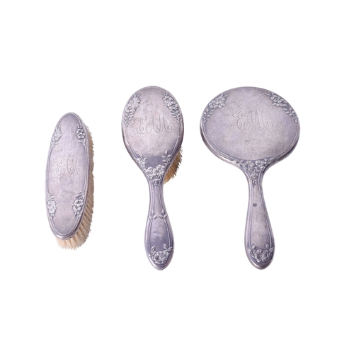 144 - An early 20th century silver backed dressing table set. Comprising two brushes and a mirror, all hav... 