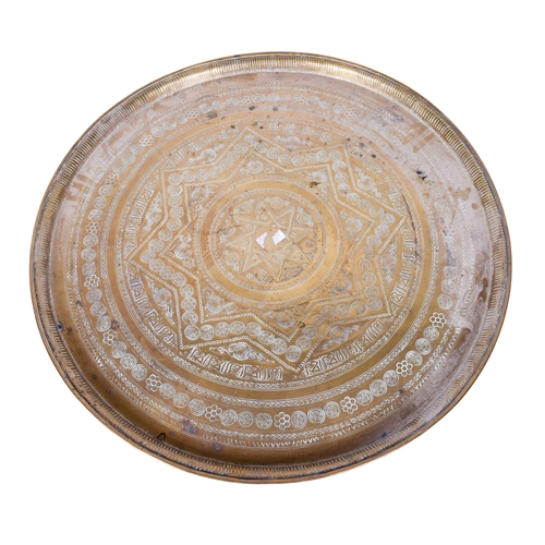 168 - An anglo Indian folding brass tray top table. The circular top engraved with stars and bands, the wo... 