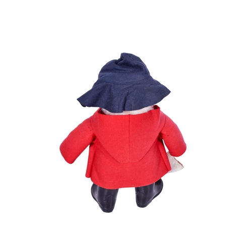 228 - A vintage plush model of Paddington Bear. Having brown hair, a red felt coat, black hat and wellingt... 
