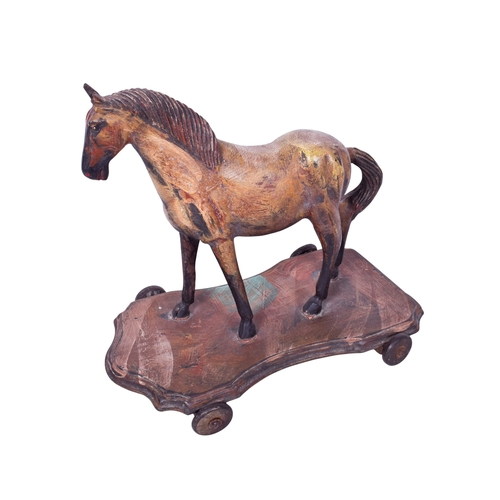 245 - A vintage pull-along wooden model of a horse. Painted and mounted on a shaped base fitted with wheel... 