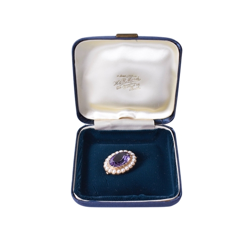 29 - A 9ct gold and amethyst brooch. The central faceted oval stone surrounded by faux half pearls, mount... 