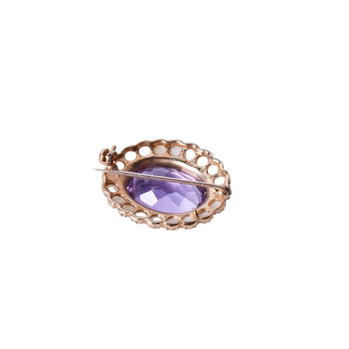 29 - A 9ct gold and amethyst brooch. The central faceted oval stone surrounded by faux half pearls, mount... 