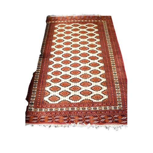 521 - A large Turkamen style wool rug on a red ground. Having multiple geometric borders with a Gul motif ... 