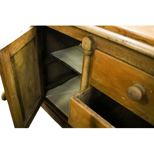 530 - An antique pine sideboard. Having three central drawers flanked by cupboards raised on turned taperi... 