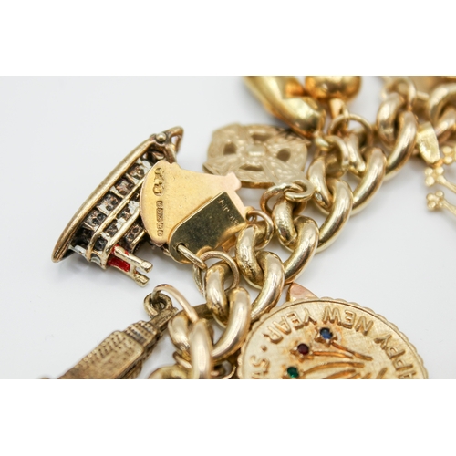 147 - A 9ct gold charm bracelet with 23 assorted gold and yellow metal charms. Charms include a post box, ... 