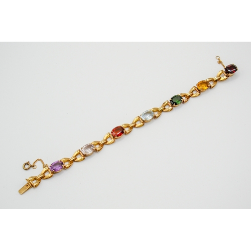 177 - A yellow metal stone set bracelet. Set with various oval cut stones in a cross link setting, includi... 