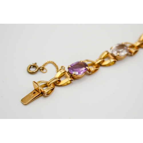 177 - A yellow metal stone set bracelet. Set with various oval cut stones in a cross link setting, includi... 