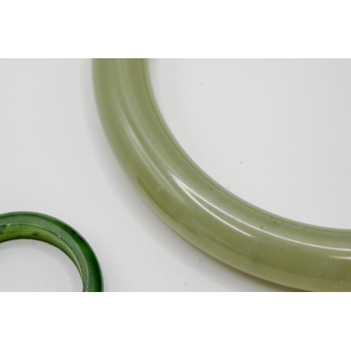 181 - A pale green jade bangle and a ring. The bangle with pale cloudy sections and a couple of darker spo... 