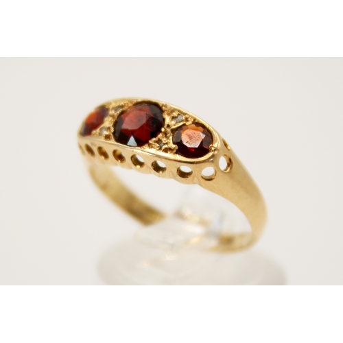 69 - An 18ct gold and garnet three stone ring. In a pierced setting, the central stone circa 4.5mm diamet... 
