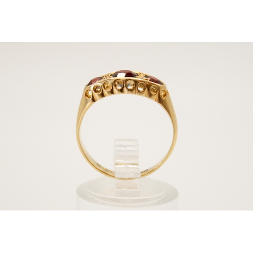 69 - An 18ct gold and garnet three stone ring. In a pierced setting, the central stone circa 4.5mm diamet... 