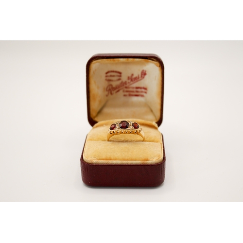 69 - An 18ct gold and garnet three stone ring. In a pierced setting, the central stone circa 4.5mm diamet... 