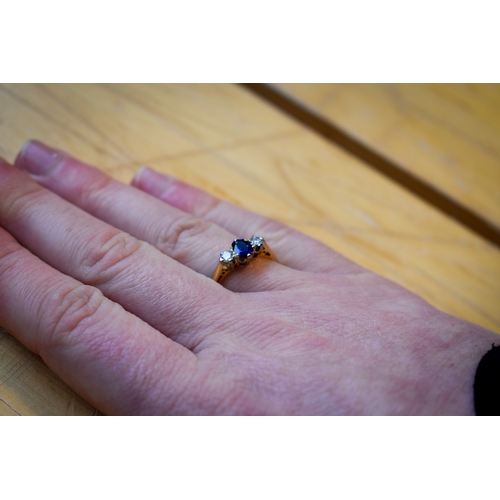 102 - A hallmarked 18ct gold three stone ring. Set with one oval faceted sapphire of 0.48 carats estimated... 