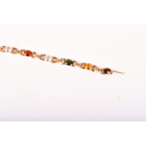 177 - A yellow metal stone set bracelet. Set with various oval cut stones in a cross link setting, includi... 