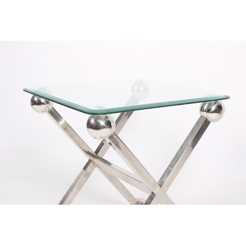 34 - A modern retro style glass top side table. Of X-frame chrome supports, terminating in oversized atom... 
