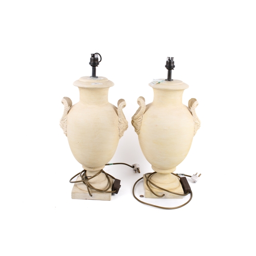 217 - A pair of ceramic table lamps. In the form neoclassical urn with horned face handles, raised on a sq... 