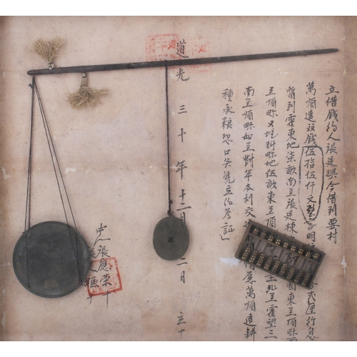 A set of Chinese balance scales in a frame. Fixed against a sheet of ...
