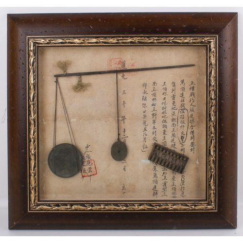 A set of Chinese balance scales in a frame. Fixed against a sheet of ...