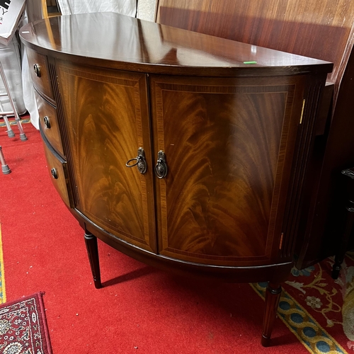 69 - Bow fronted flamed mahogany sideboard with double cupboard ends and triple drawer centre on turn leg... 