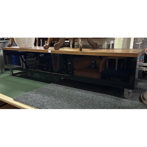 24 - TEAK AND BLACK GLASS TV STAND WITH CUSHION CLOSE DOORS ON CHROME LEGS