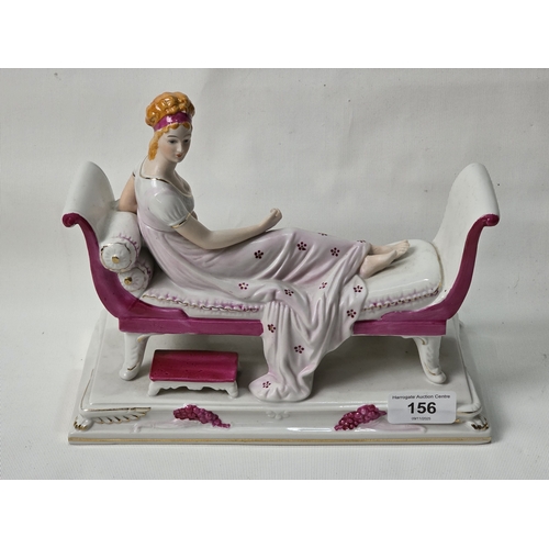 156 - PORCELAIN FIGURINE OF RECLINING LADY ON CHAISE LONGUE, 9” WIDE