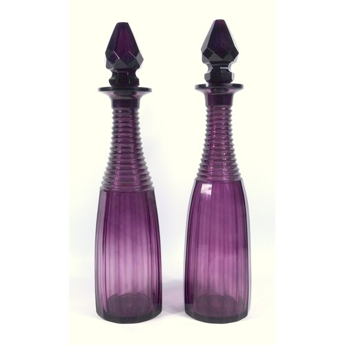 566 - A pair of Victorian amethyst glass decanters, with step cut and faceted decoration, H. 36 cm.