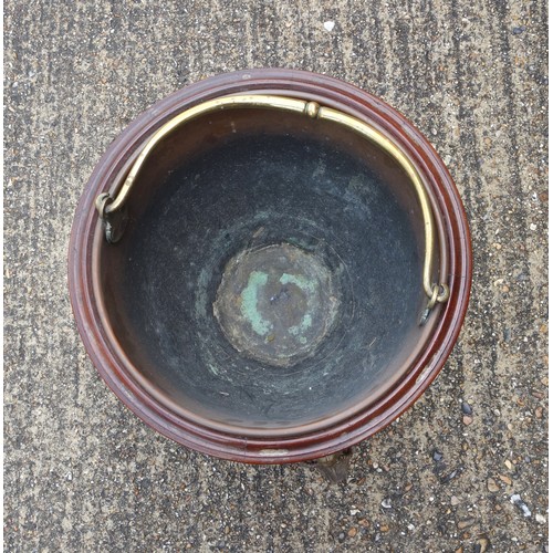 331 - Edwardian copper coal cauldron with a brass swing handle, on a mahogany stand with brass lion mounts... 